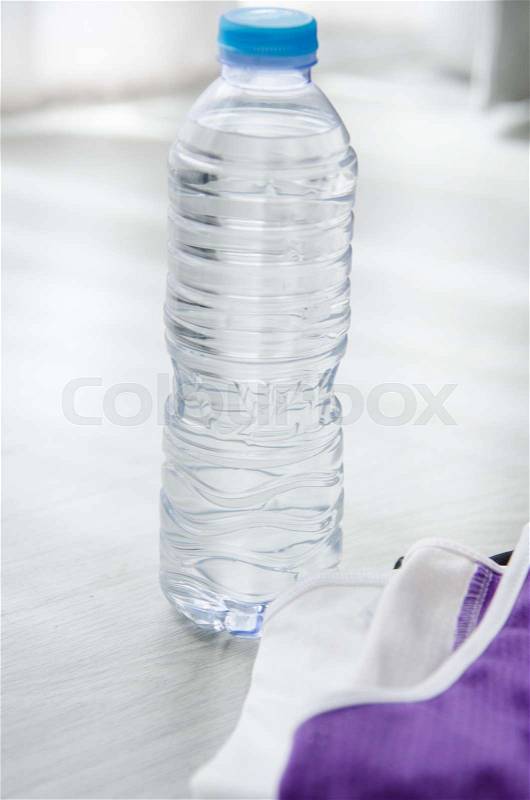 Bottle of water and sport wear on the floor near window light. Healthy lifestyle concept, stock photo