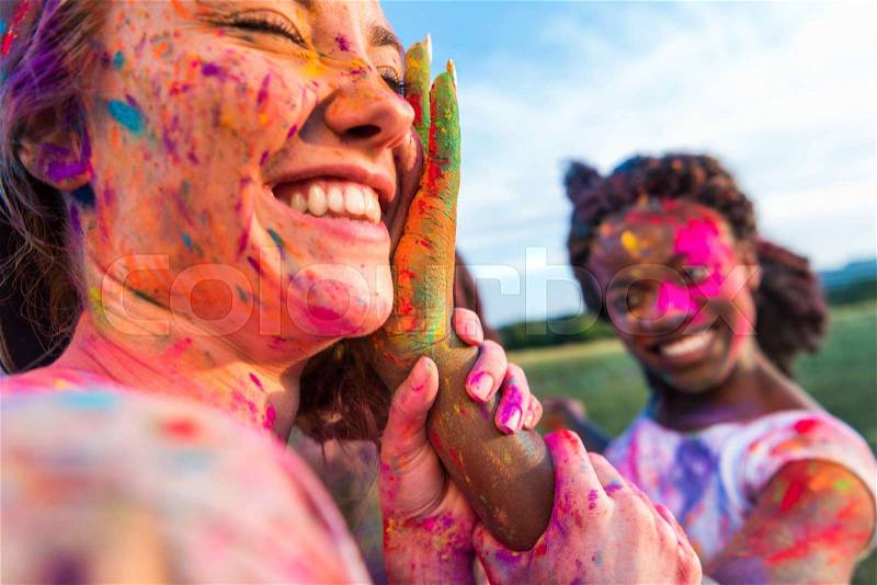 Happy young multiethnic friends having fun with colorful powder at holi festival of colors, stock photo