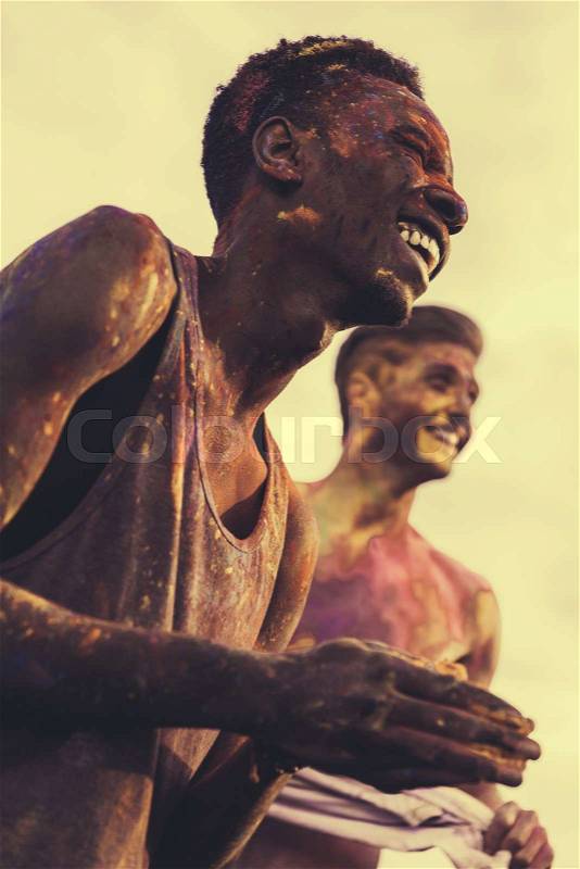 Happy young multiethnic men with colorful paint on clothes and bodies having fun together at holi festival, stock photo