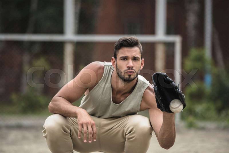 Young handsome man catching baseball ball on court, stock photo