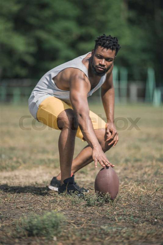 Young handsome african american male football player with ball on court, stock photo