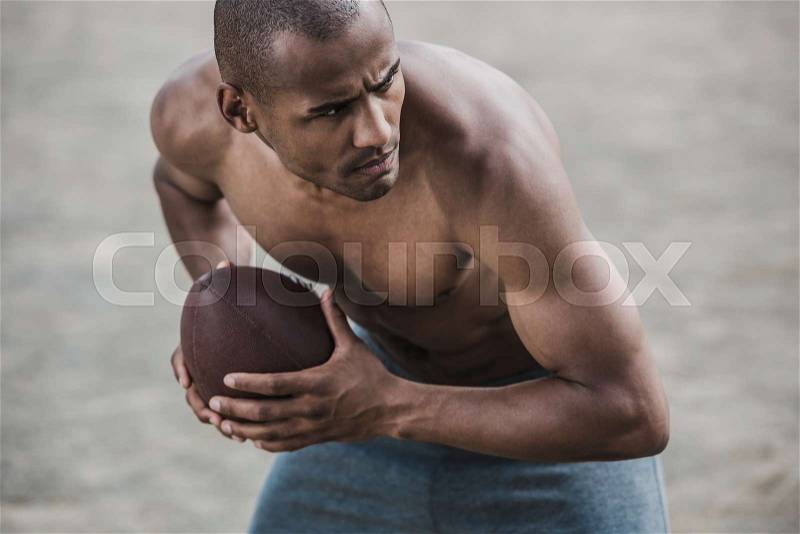 Young handsome african american male football player with ball , stock photo