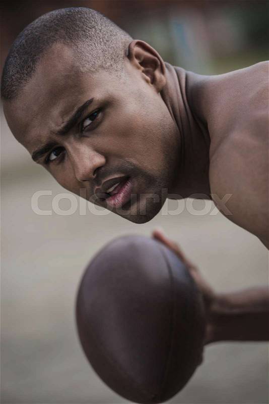 Young handsome african american male football player with ball , stock photo