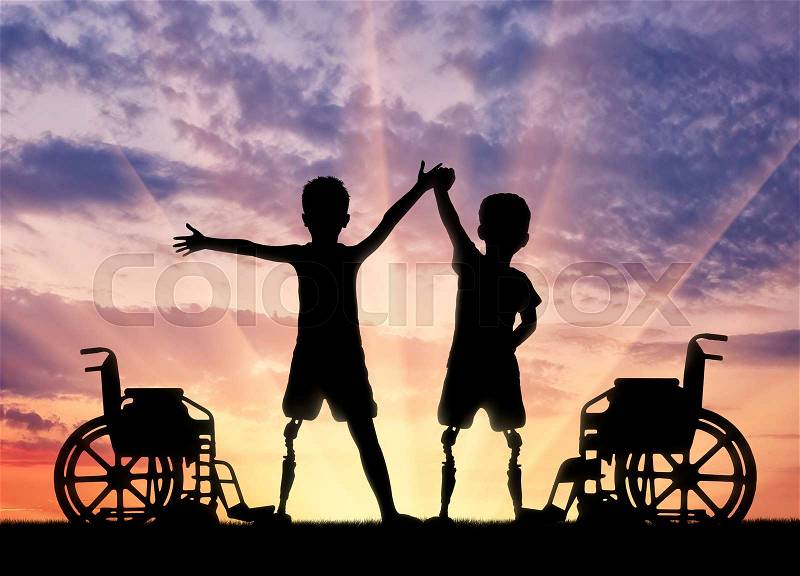 Children\'s disability concept. Two happy boy with a disability with a prosthetic leg standing near a wheelchair on sunset background, stock photo