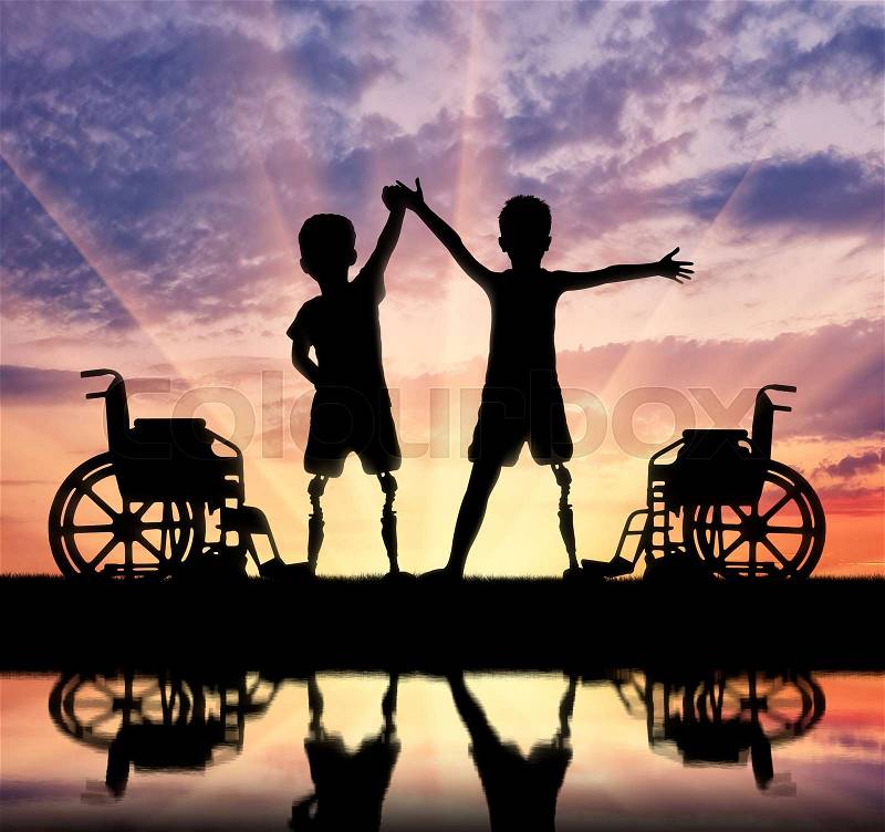 Children\'s disability concept. Two happy boy with a disability with a prosthetic leg standing near a wheelchair at the river with their reflection, stock photo