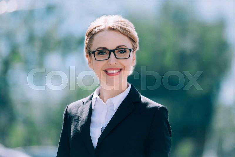 Portrait of beautiful blonde mature businesswoman in eyeglasses smiling at camera, stock photo