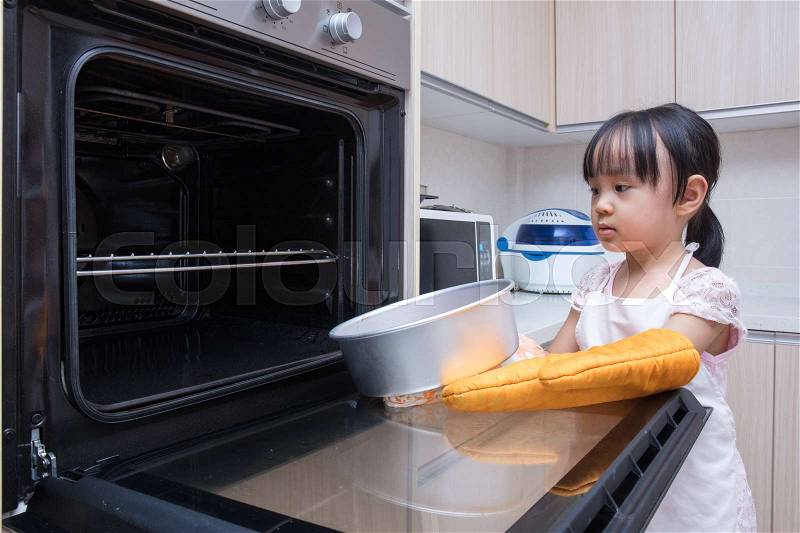 Asian Chinese little girl baking cake at home in the kitchen, stock photo