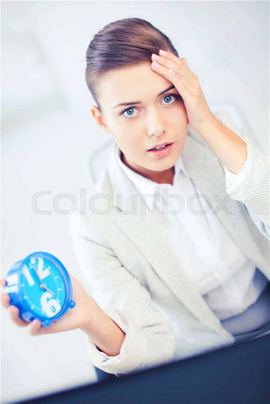 Business and time management concept - stressed businesswoman holding clock, stock photo