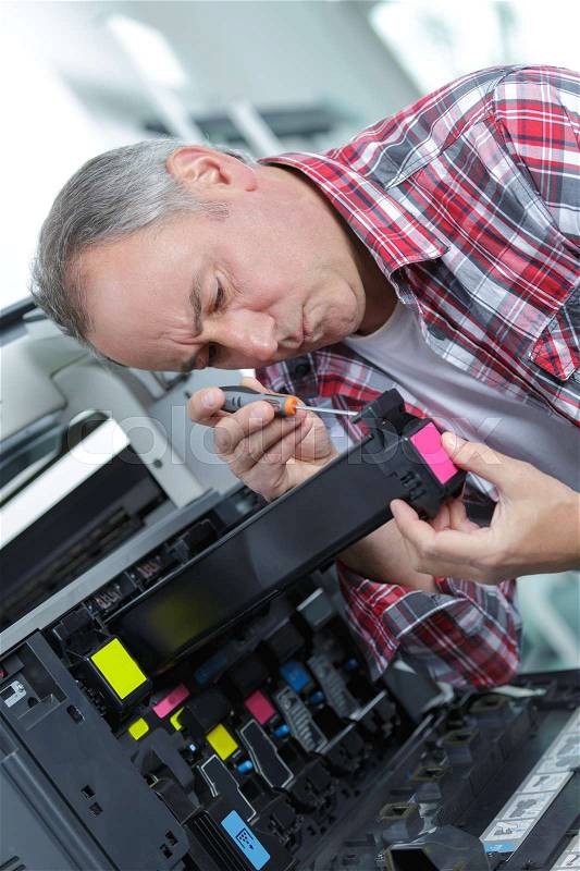 Male tech trying to repair the office printer, stock photo