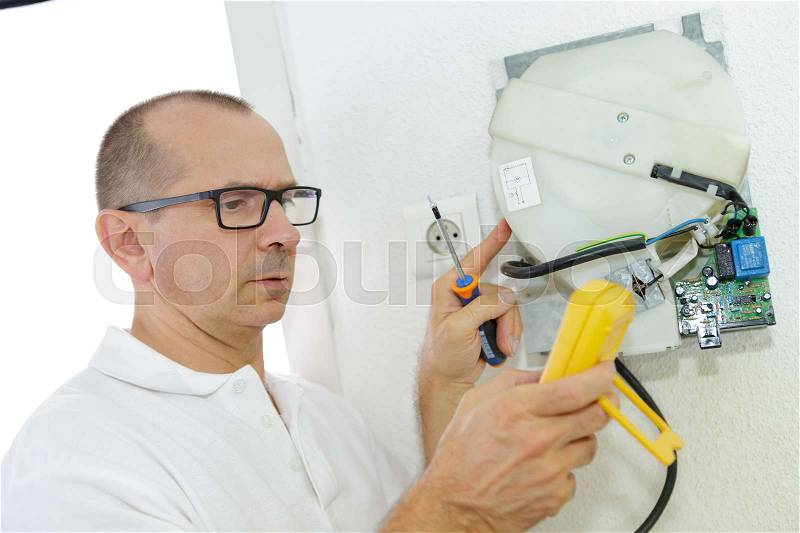 Mature electrician working with cables and wires, stock photo