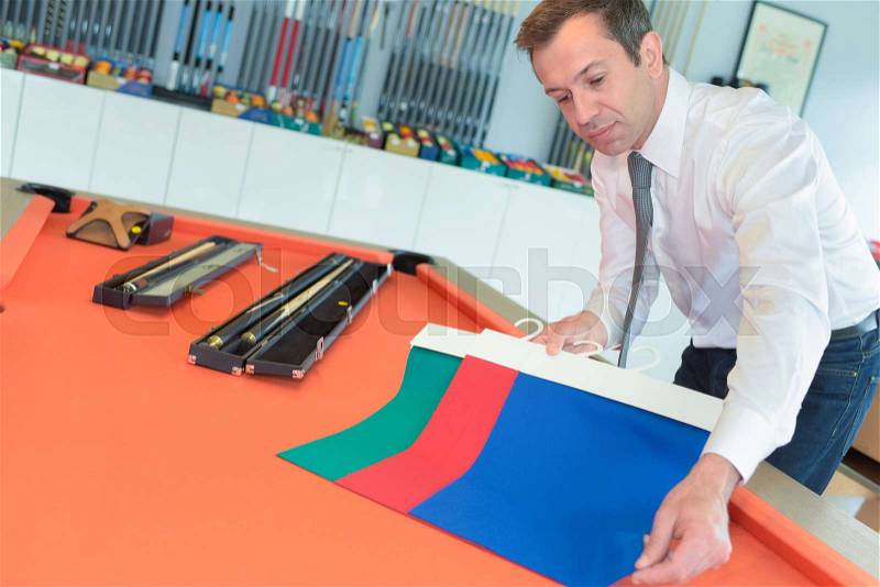 Shop owner showing different colors for pool table, stock photo