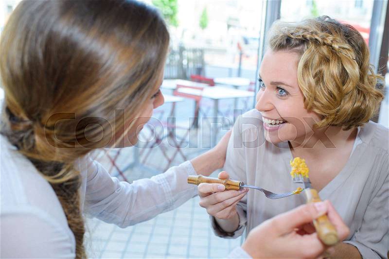 Two women eating out in fast food restaurant talking, stock photo