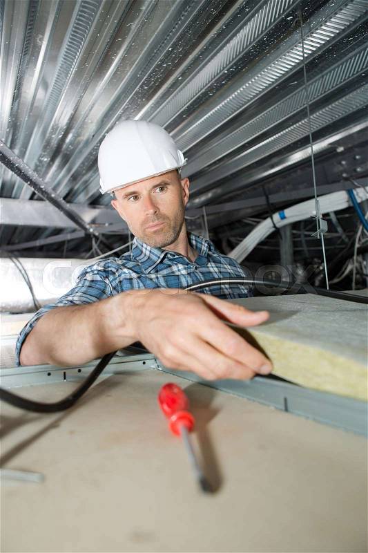Roofer builder worker installing roof insulation material, stock photo