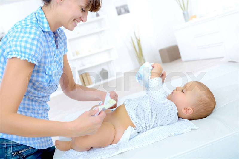 Mother changing baby nappy, stock photo