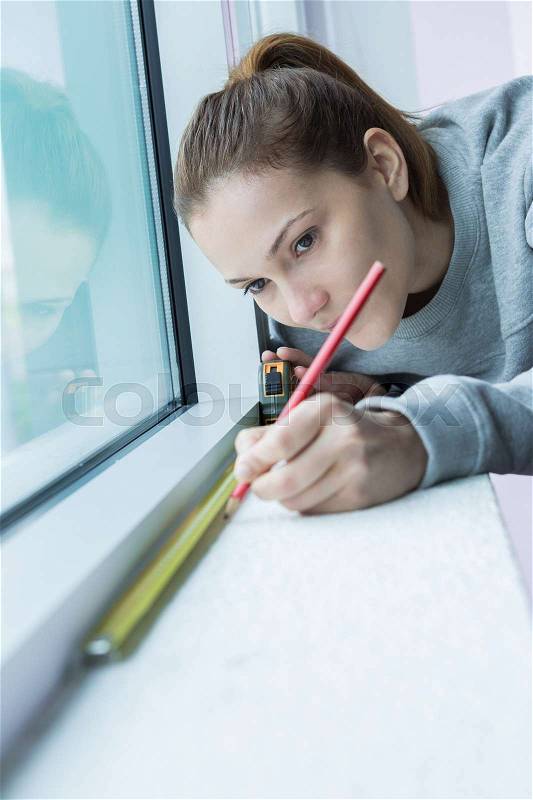 Female worker measuring window glass, stock photo