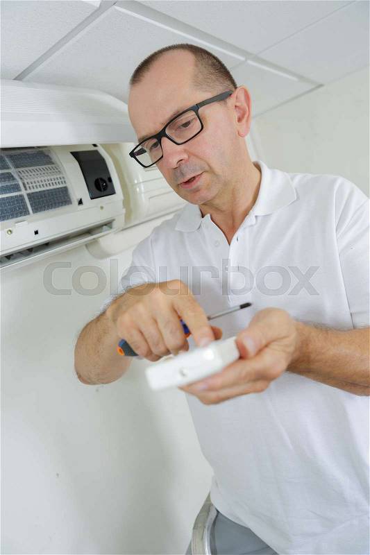 Air conditioning technician preparing to install new air conditioner, stock photo