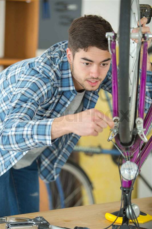 Mechanic setting up chain on bicycle in workshop, stock photo
