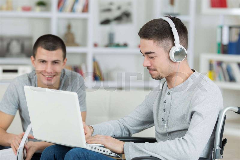 Smiling disabled student with classmate working at home, stock photo