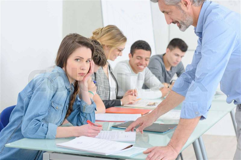 Frustrated teenage girl at a school class, stock photo