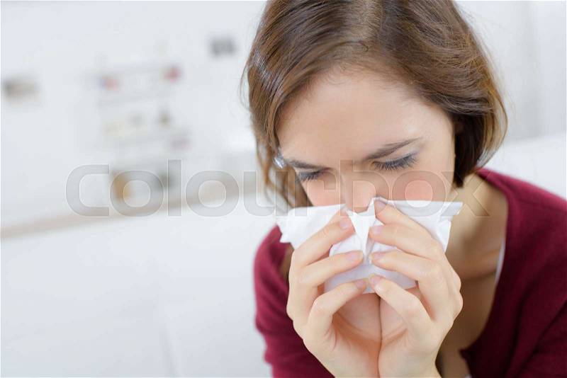 Cold woman holding handkerchieif blowing nose, stock photo