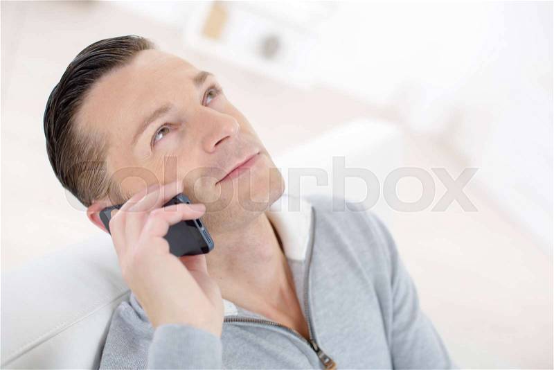 Man in sofa talking on phone, stock photo