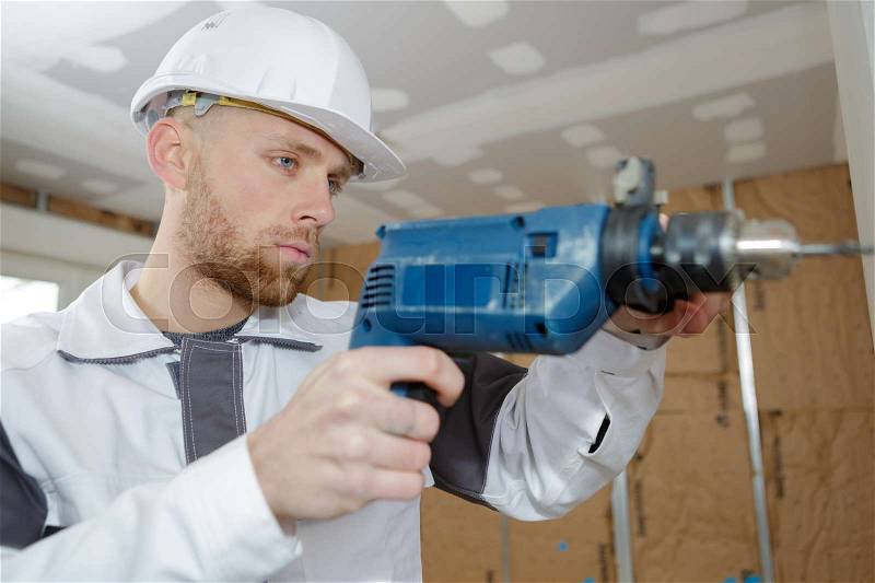 Contractor uses hammer drill to drill the concrete wall, stock photo