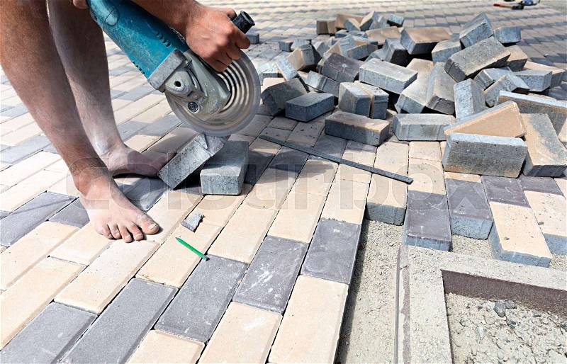 The worker cuts a bar of paving slabs for the final laying on the terrace, stock photo