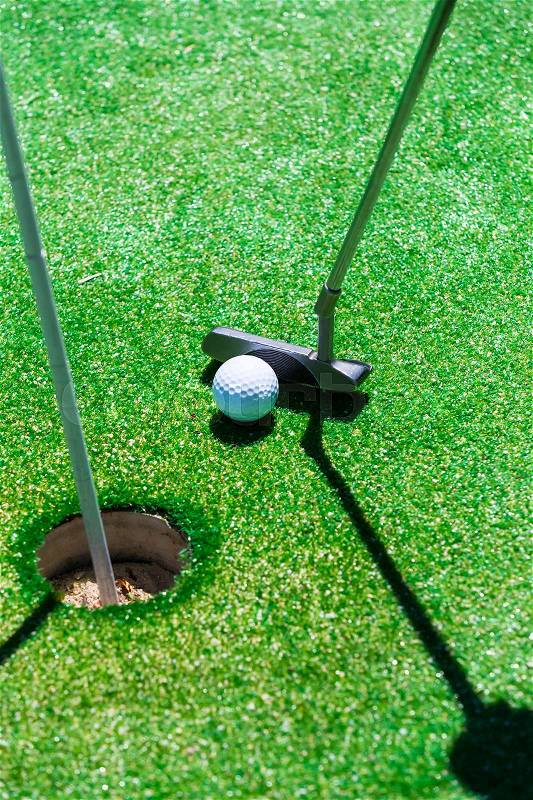 Stick with a ball on an artificial golf course, stock photo