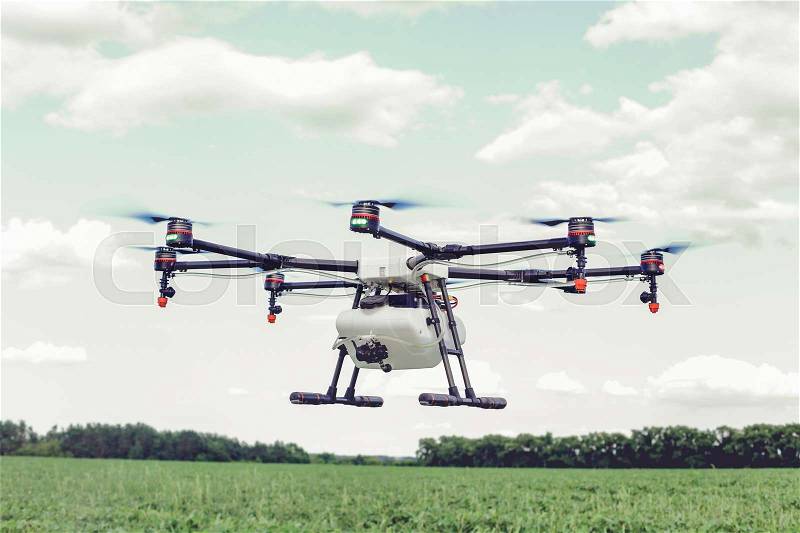 Professional agriculture drone flying and green wheat field, Hovering drone flies in blue sky and taking pictures of green hills, stock photo