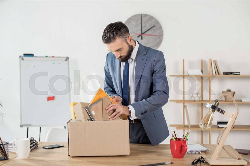 Portrait of fired sad businessman packing office supplies at workplace, stock photo