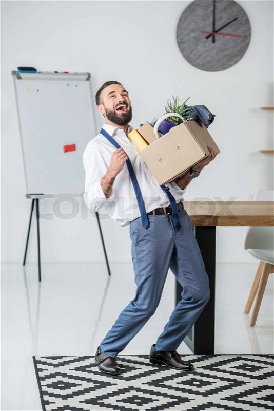 Happy businessman with cardboard box in hands quitting job, stock photo