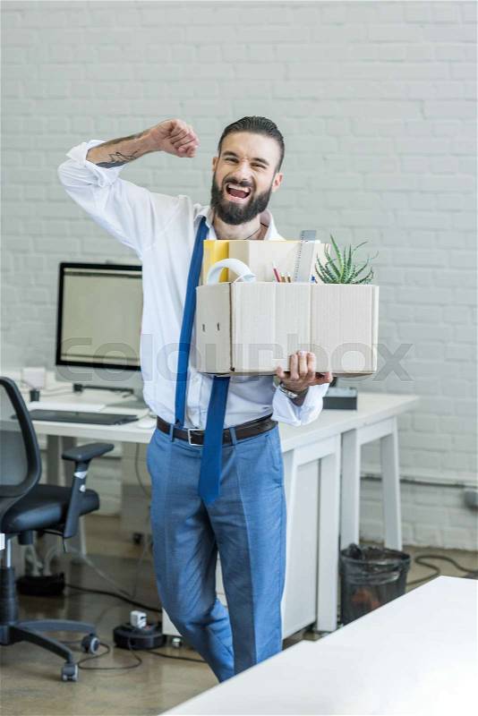 Excited businessman with cardboard box in hand quitting job, stock photo