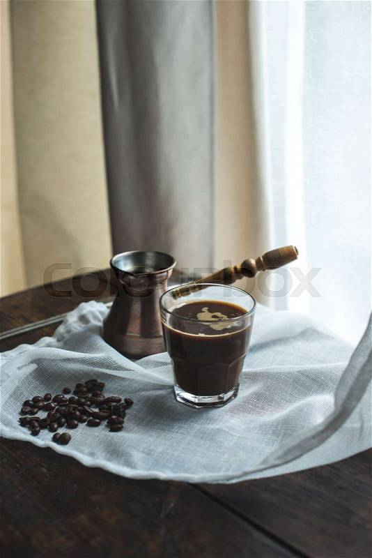 Turkish coffee pot with glass of coffee on white cloth with coffee beans, stock photo