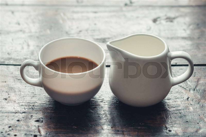 White cup of coffee with milk and jug on wooden rustic table, stock photo