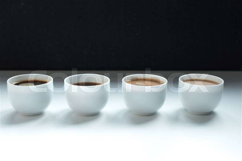 Different kinds of coffee in row on white table, close-up view, stock photo