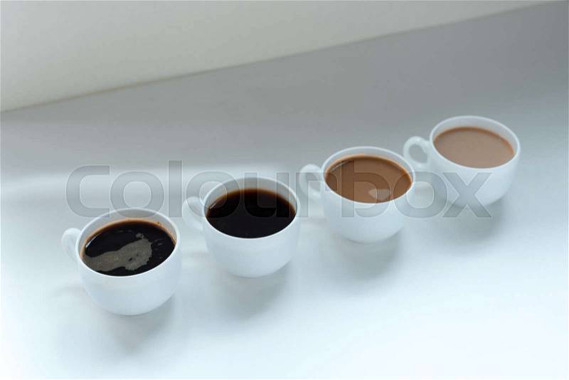 Different kinds of coffee in row on white table, close-up view, stock photo