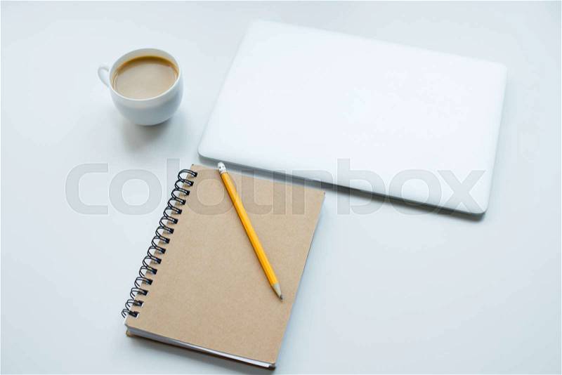 Laptop computer, notepad with pencil and cup of coffee isolated on white, stock photo