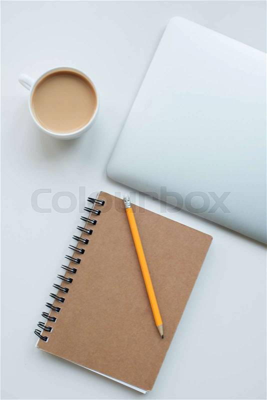 Flat lay with laptop computer, notepad with pencil and cup of coffee isolated on white, stock photo