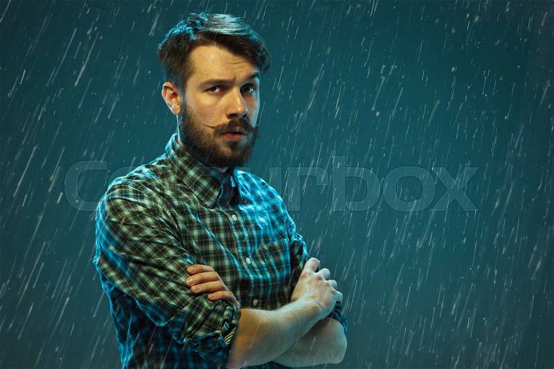 The young happy man looking at camera on rain studio background, stock photo