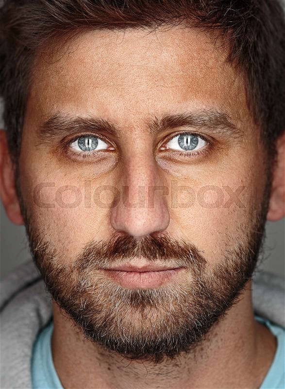 The young happy man looking at camera on gray, stock photo