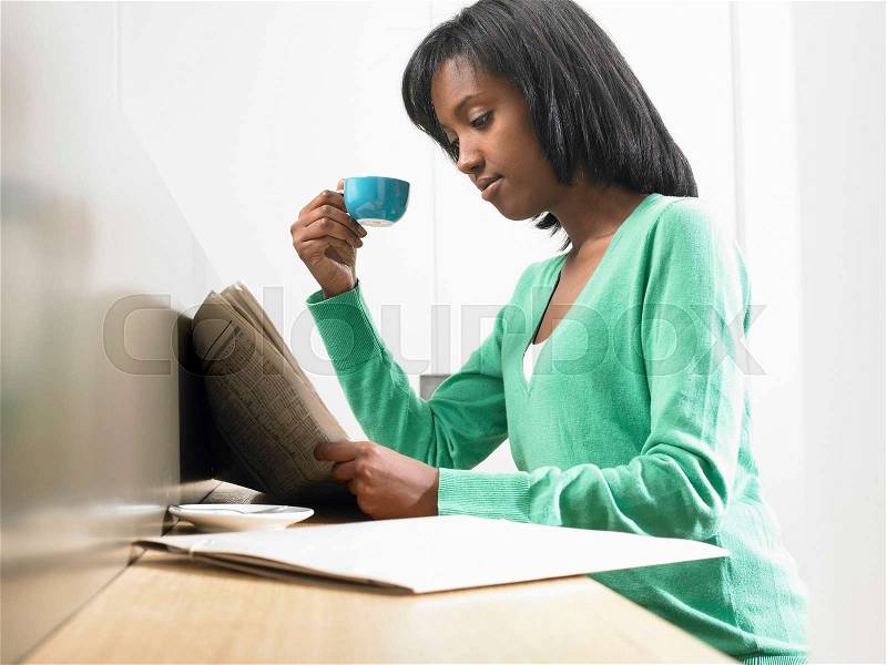 Woman having a coffee, reading newspaper, stock photo