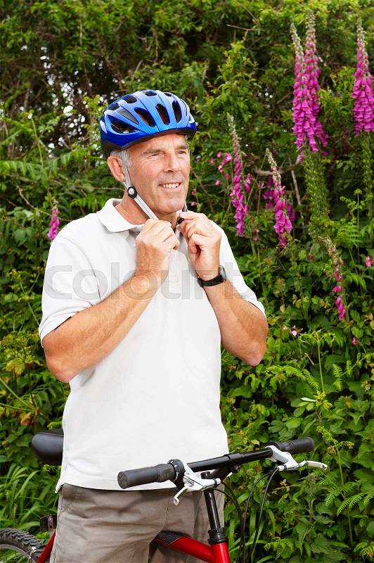 Senior man fastening cycle helmet, stock photo