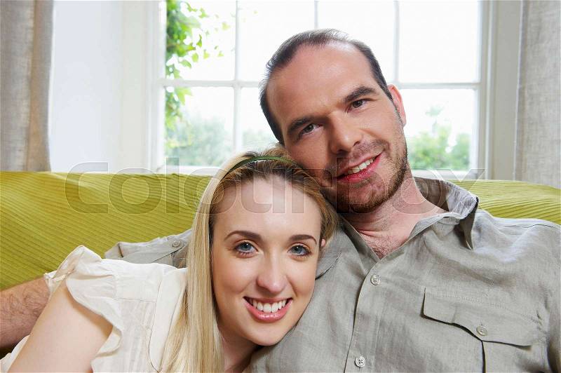 Couple sitting on couch, smiling, stock photo