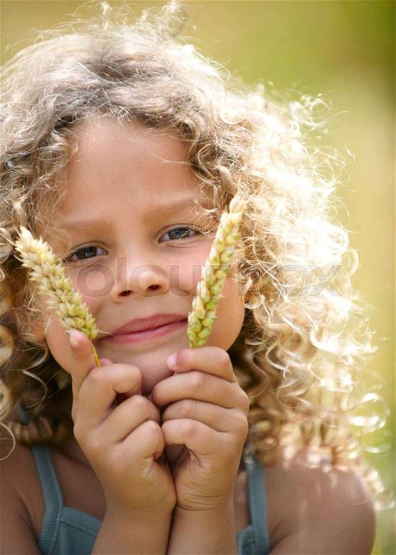 Young girl holds up ears of corn, stock photo