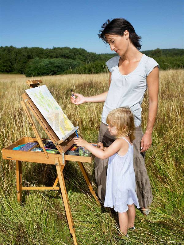 Mother and daughter painting in a field, stock photo