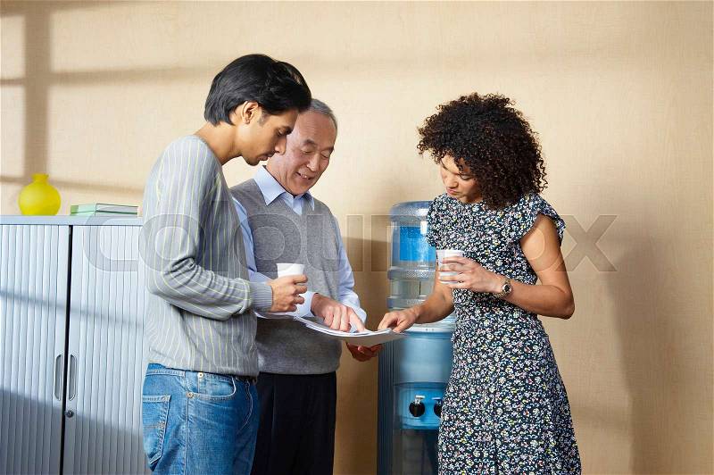 Office workers standing by water cooler, stock photo