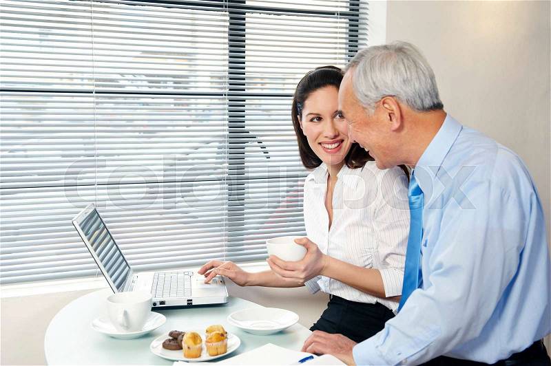 Co-workers in cafe with laptop smiling, stock photo