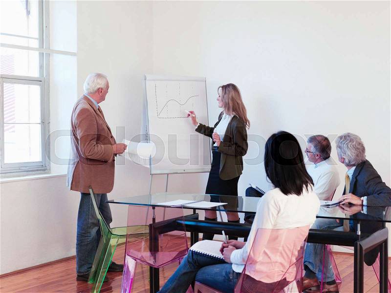 Co-workers giving presentation in office, stock photo