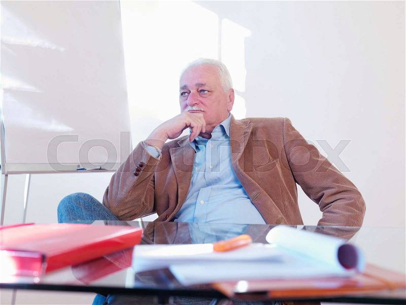 Senior executive sitting at desk, stock photo