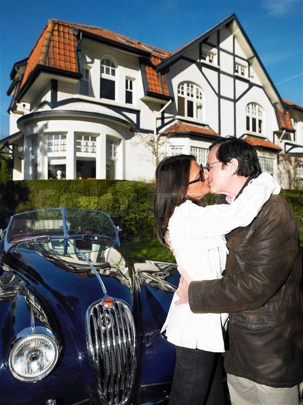 Couple in front of their house and car, stock photo